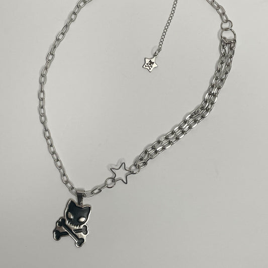 Image shows a long embossed roll chain with a black enamel 1.5” pendant of a cat skull and crossbones 