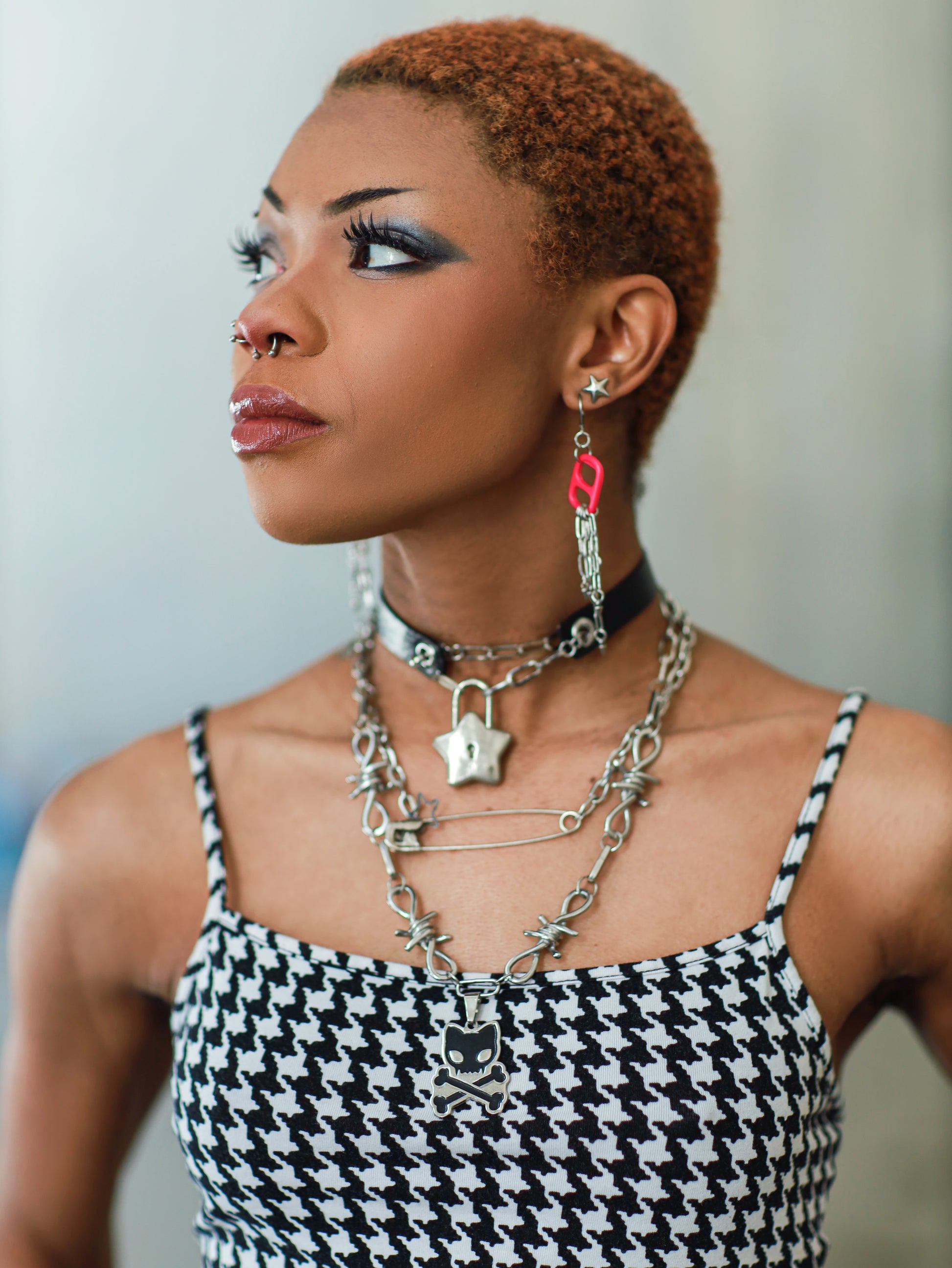 Image shows dark-skinned woman with shaved head and punk clothing with the barbed wire toxicat on her neck as well as the achievement unlocked leather choker 