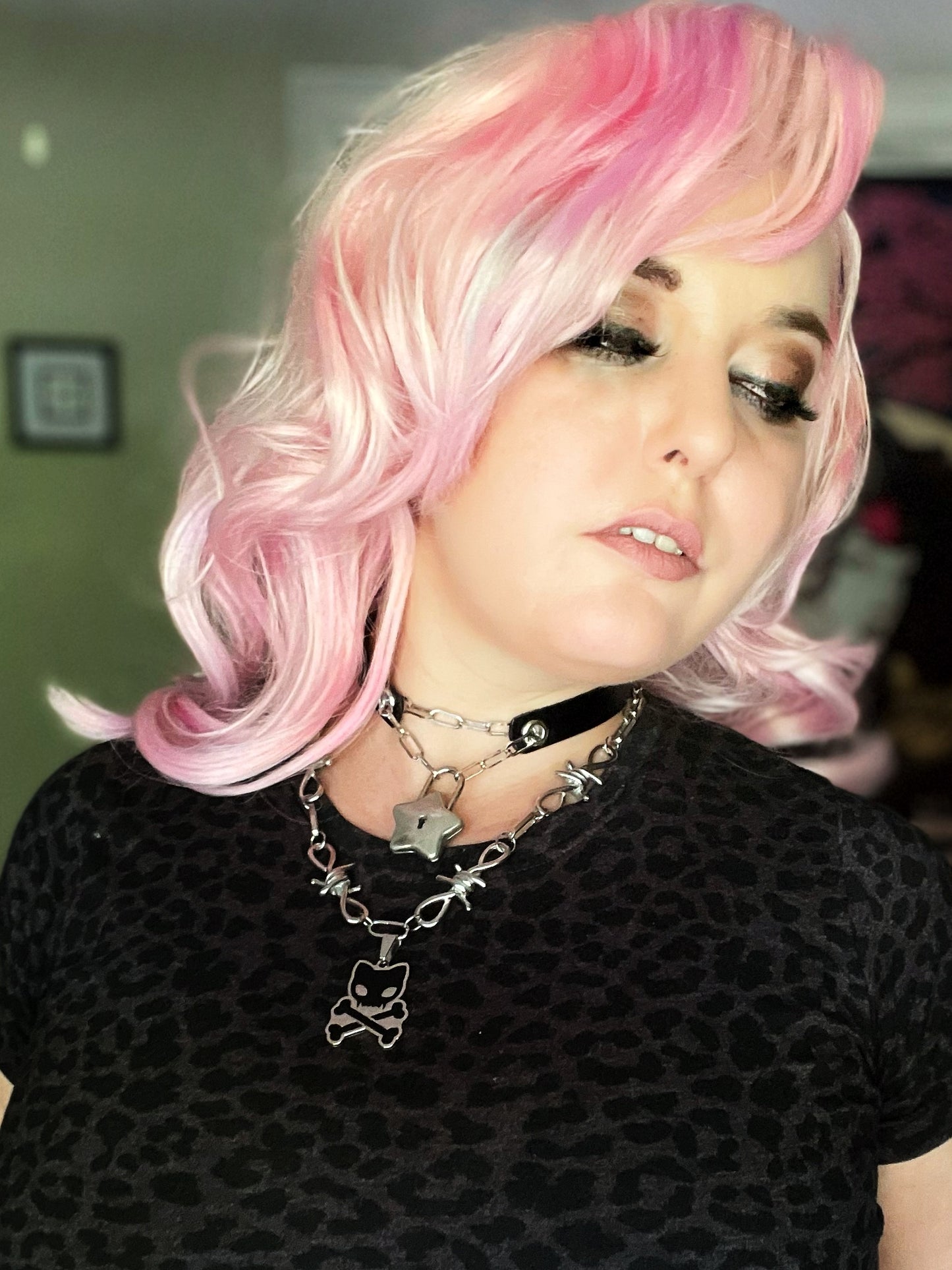 Image shows pink haired white woman wearing the barbed wire toxicat necklace over a black leopard print shirt 