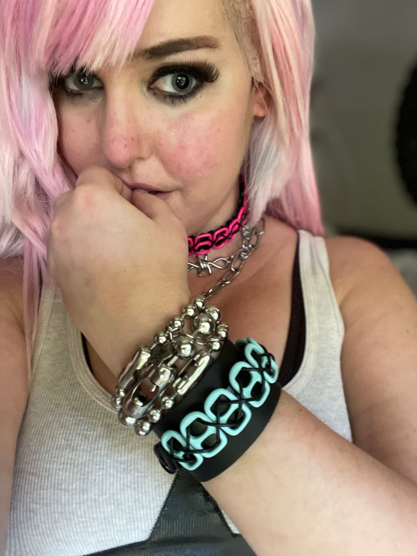 Image shows three ball chain bracelets among leather cuffs on a woman’s arm 