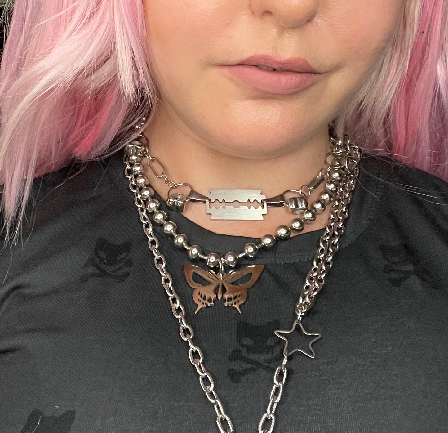 Closeup of woman wearing the necklace among other steel jewelry 