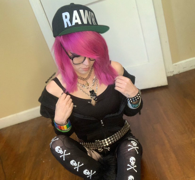 Image showing girl with hot pink hair wearing glasses and a flat brimmed hat that says RAWR in large lettings wearing scne punk clothing and punk metal jewelry